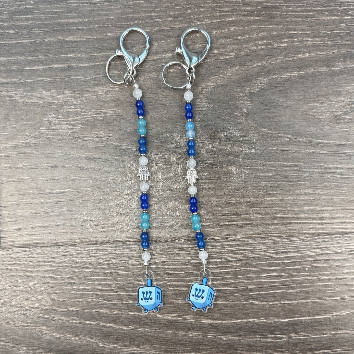 Pair of beaded keychains with dreidel charms on a wooden surface