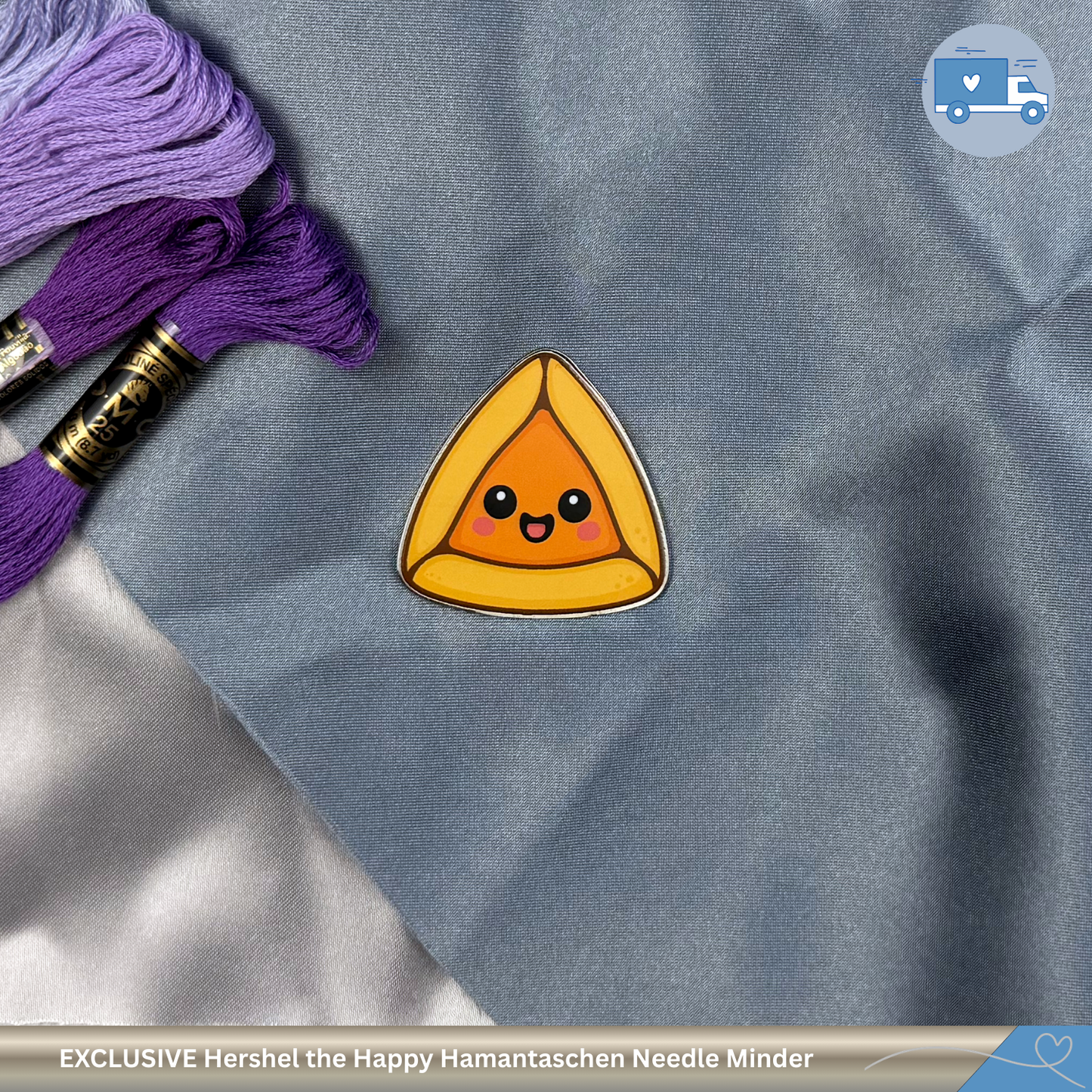 Happy Hamantaschen needle minder with purple embroidery floss on a gray fabric background