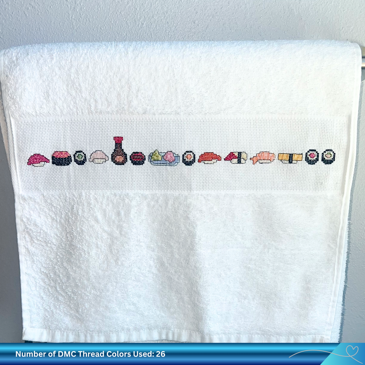 White towel with hand embroidered sushi designs on a gray background