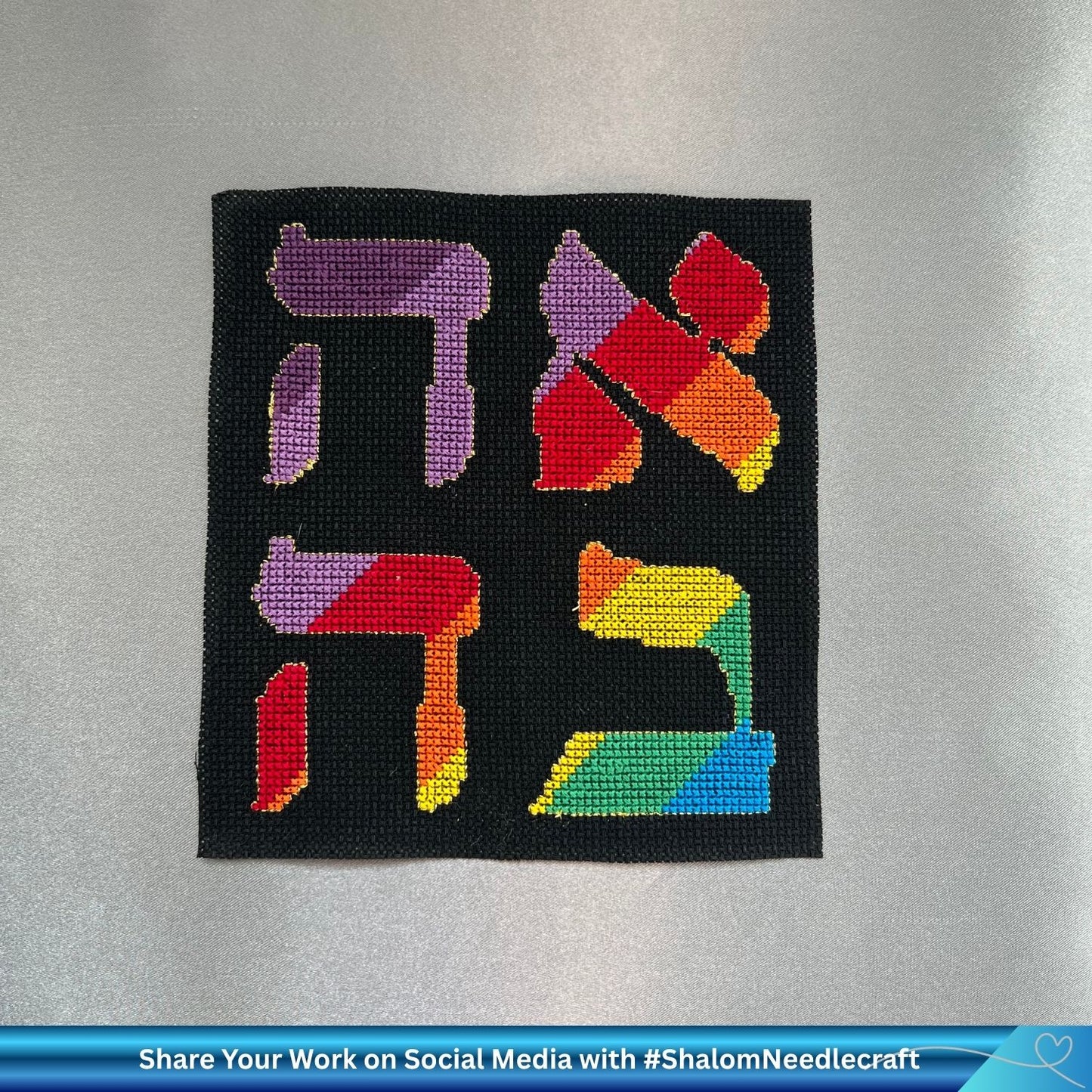 Hand embroidered word Love (Ahava) in rainbow colors on black Aida cotton