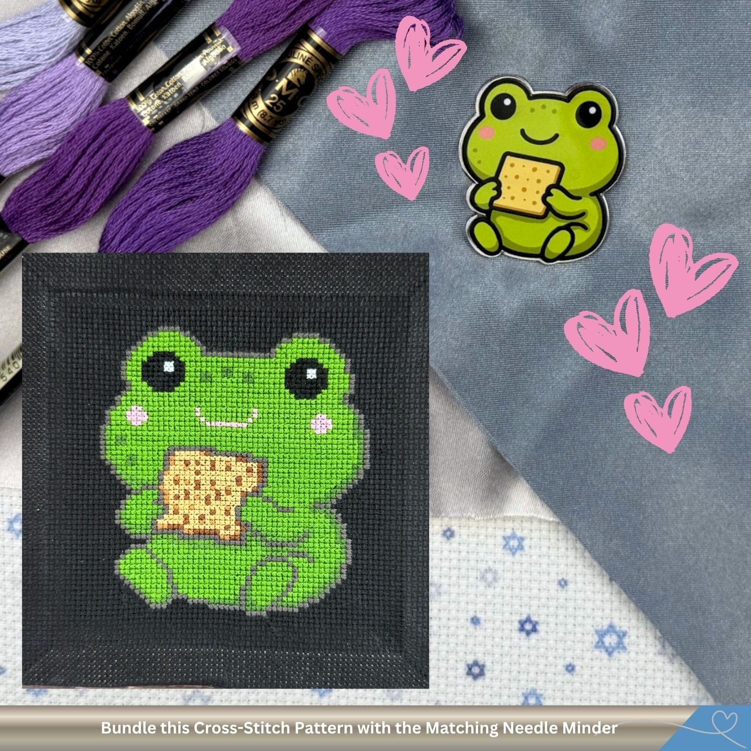 Cross-stitched frog pattern with matching needle minder on a textured surface with embroidery threads and hearts.