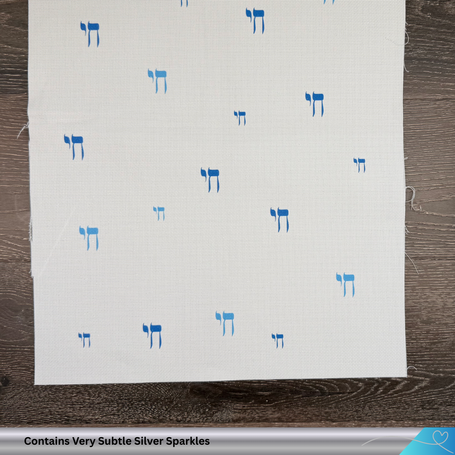 White fabric with blue Hebrew text patterns on a wooden surface. Contains  hints of silver glitter.