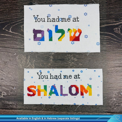 Two cross-stitch projects - the one on top in Hebrew and the one below in English. Both say "You had me at Shalom" in rainbow letters.