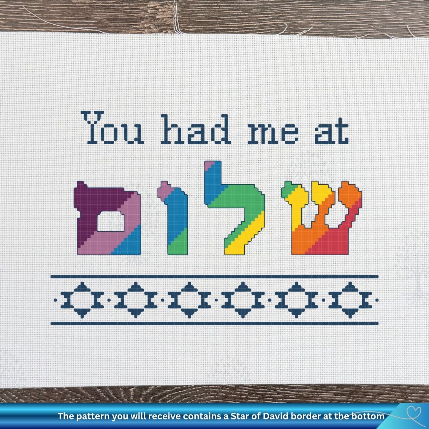 Cross-stitch pattern with colorful Hebrew letters and text on a white fabric background.