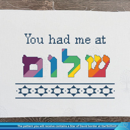 Cross-stitch pattern with colorful Hebrew letters and text on a white fabric background.