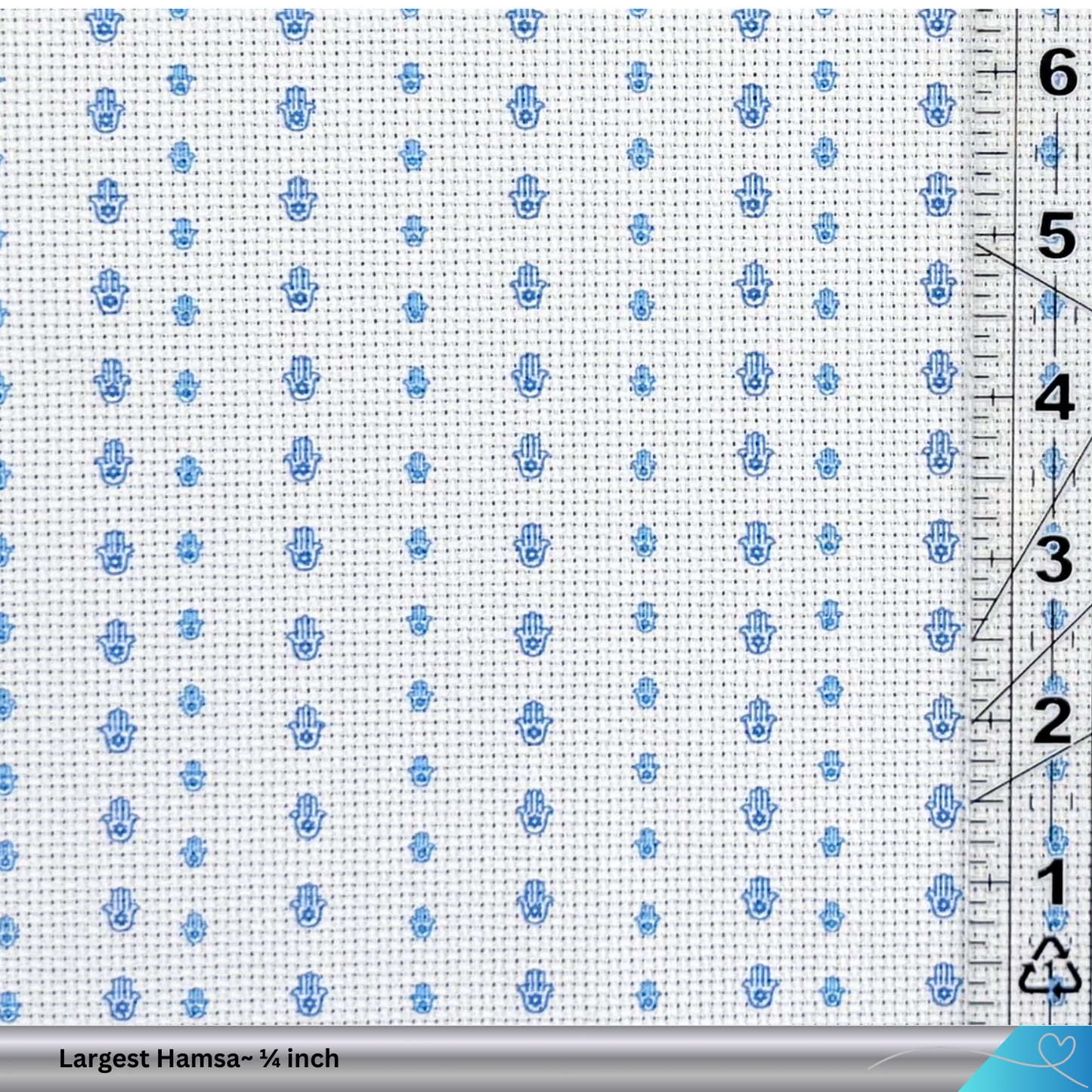 Cross-stitch pattern with blue Hamsa hands on a white fabric background, ruler for scale.
