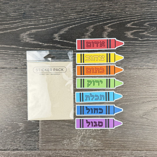 Pack of colorful crayon-shaped stickers with Hebrew text on a wooden surface