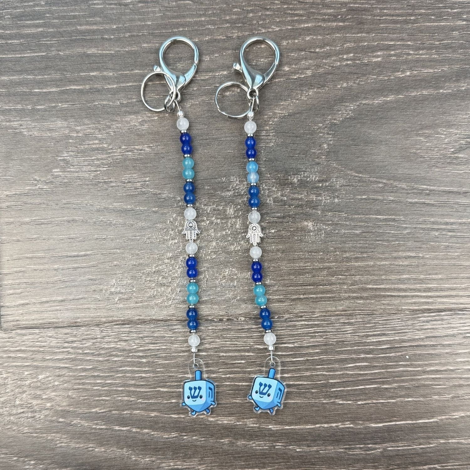 Pair of beaded keychains with dreidel charms on a wooden surface