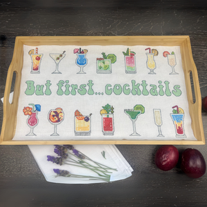 Wooden tray with a cross stitch pattern featuring cocktail illustrations and text 'But first... cocktails'.