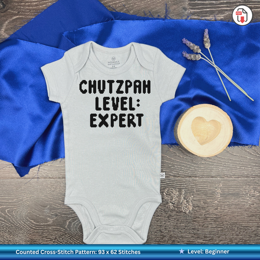 Baby onesie with 'CHUTZPAH LEVEL: EXPERT' text on a blue fabric background