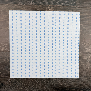 Piece of cotton Aida with blue Hamsa symbols printed lying against a wooden background