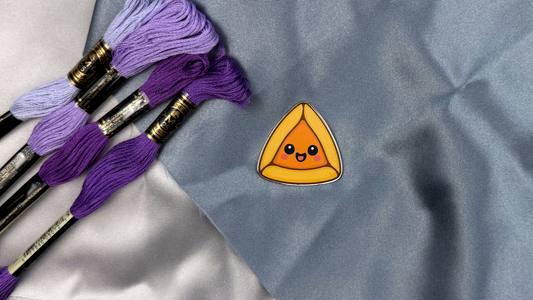 Hamataschen needle minder against embroidery background