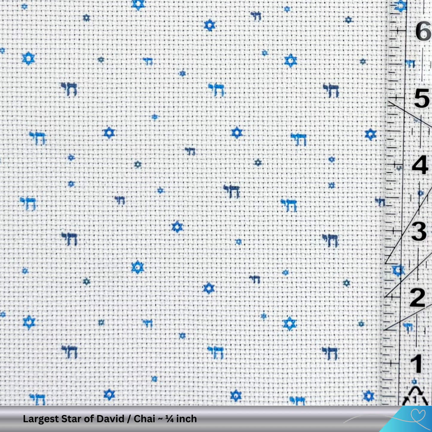 Cross-stitch fabric with blue Star of David and Chai patterns and a ruler for scale.