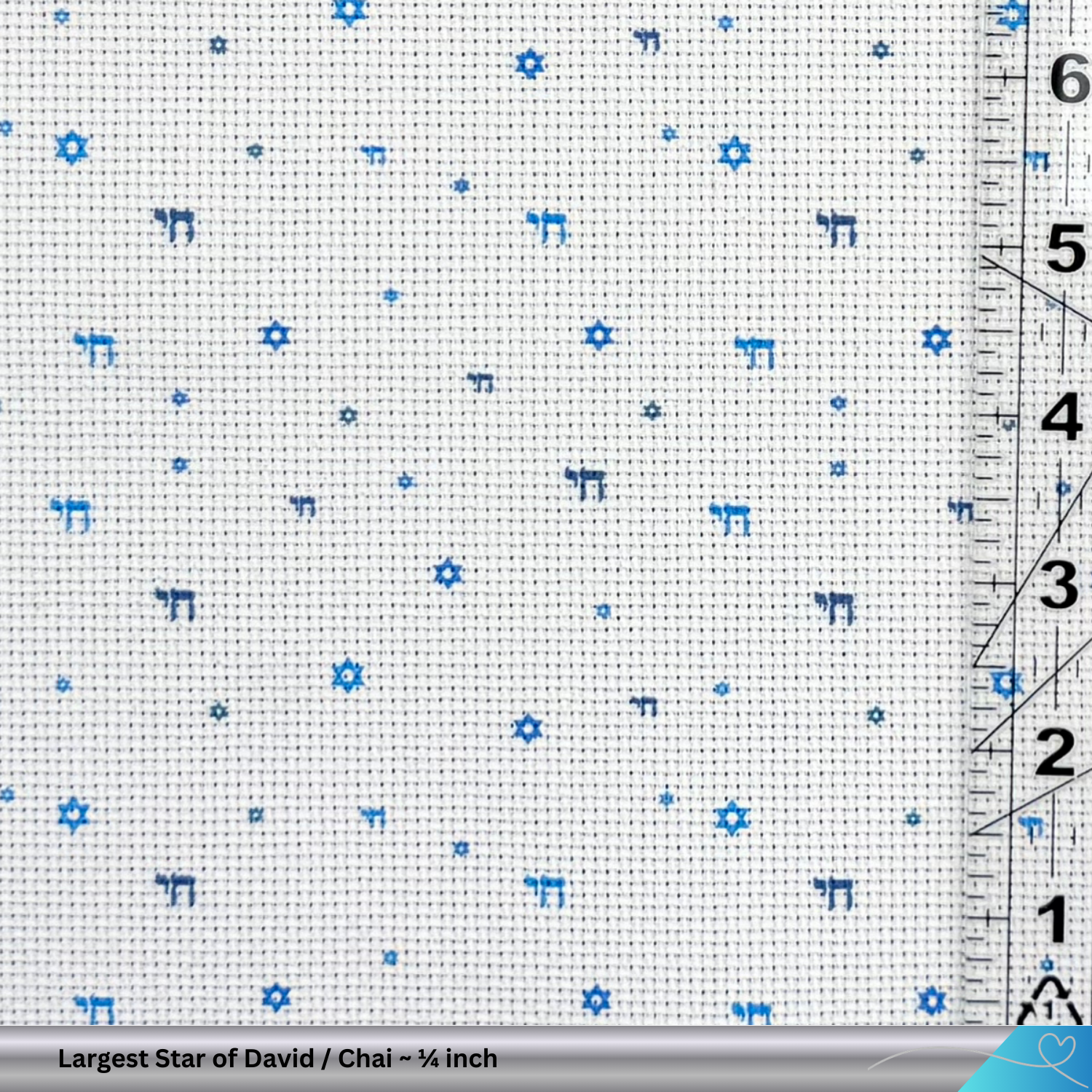 Cross-stitch fabric with blue Star of David and Chai patterns and a ruler for scale.