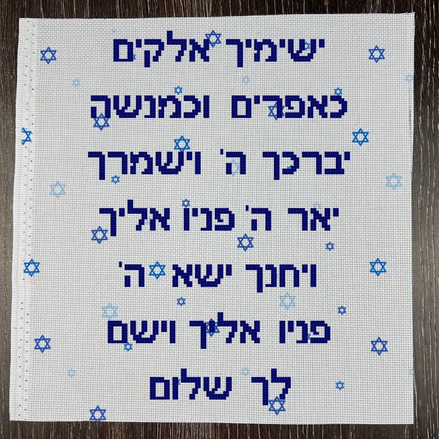 Embroidered fabric with Hebrew text and star of david fabric on a wooden surface