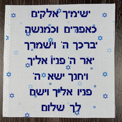 Embroidered fabric with Hebrew text and star of david fabric on a wooden surface