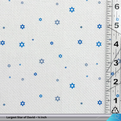 Cross-stitch fabric with blue Star of David patterns and a ruler for scale.