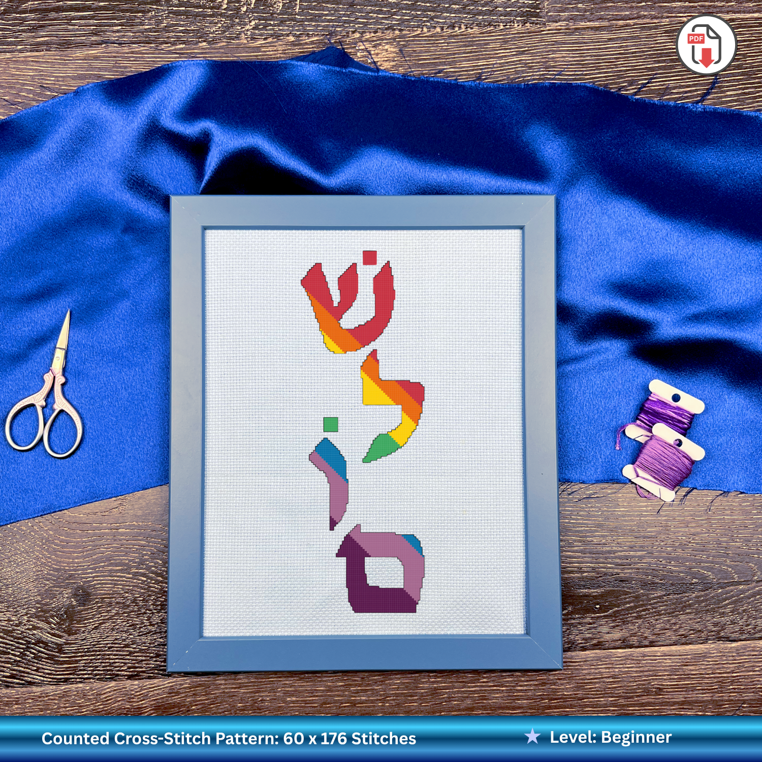 Framed cross-stitch pattern with colorful Hebrew letters on a blue fabric background
