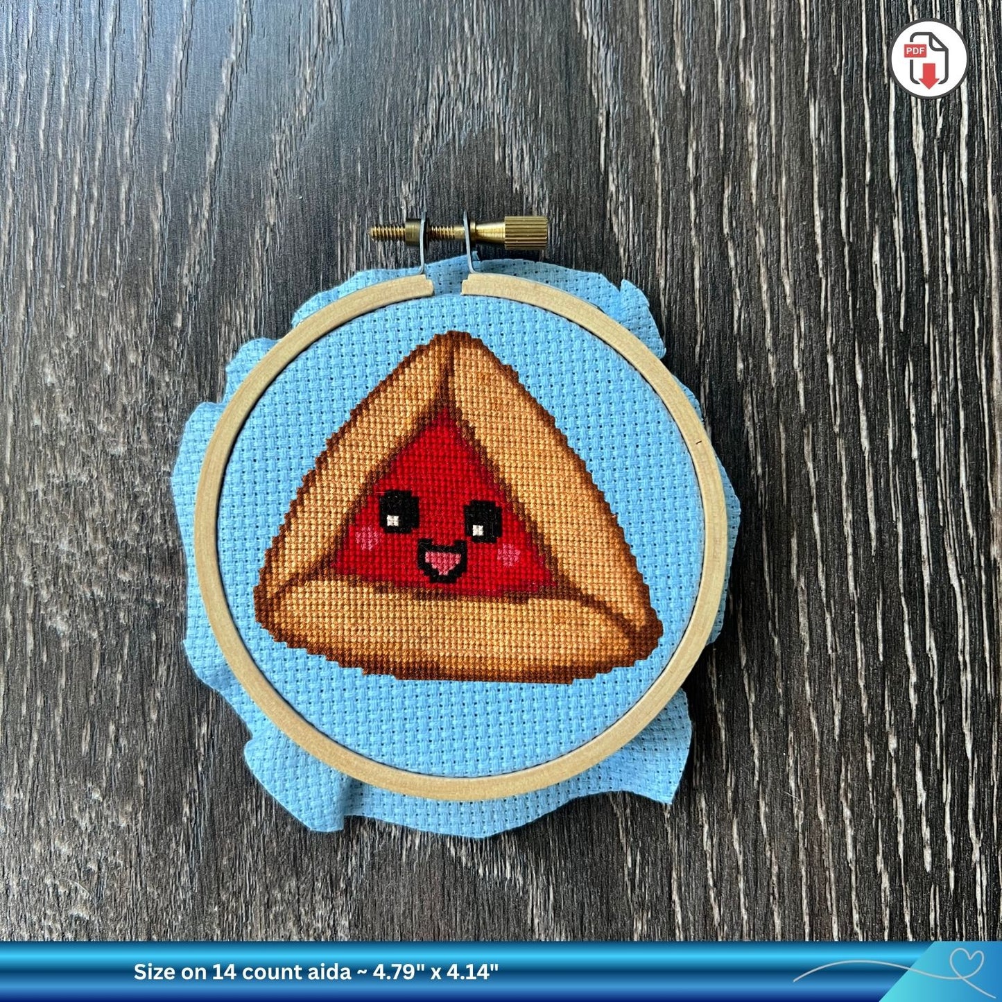 Cross-stitched pie design in an embroidery hoop on a wooden surface