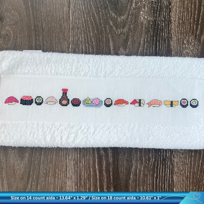 Cross-stitched sushi pattern on a white towel with text about size and fabric type.