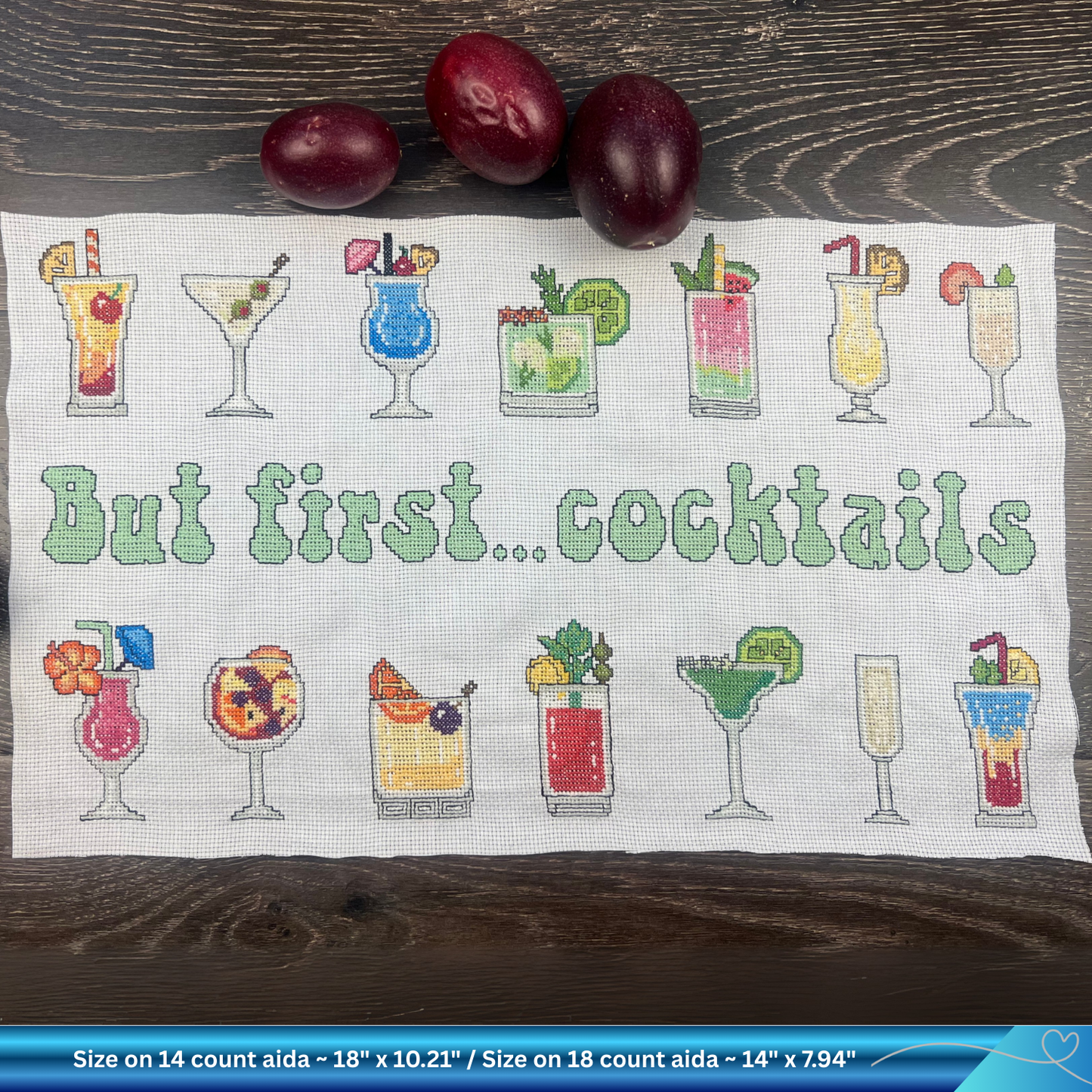 Cross-stitched towel with cocktail designs and 'But first... cocktails' text on a wooden surface.
