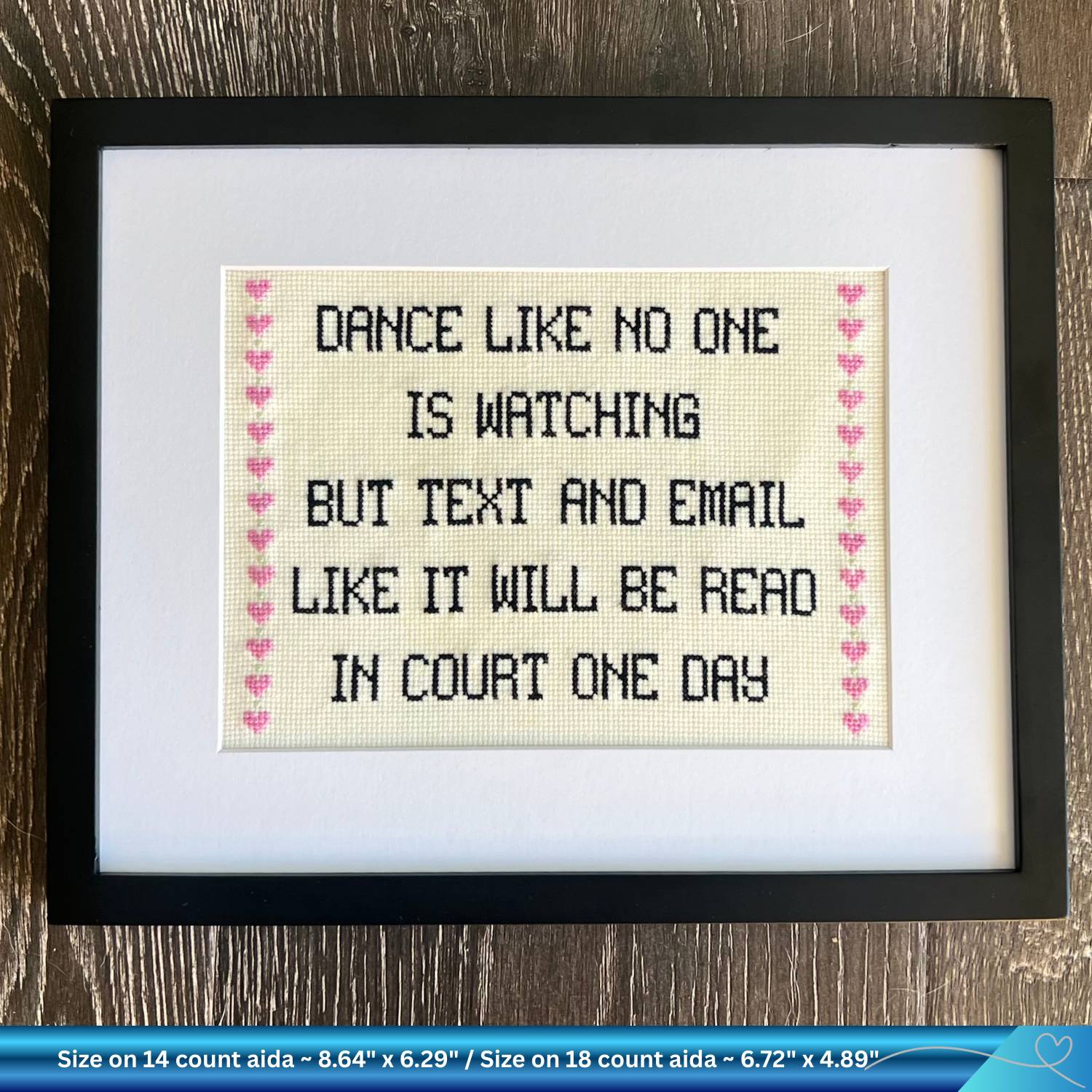 Framed humorous legal cross-stitched text on a wooden surface
