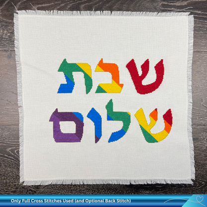 Colorful Hebrew text on a white Aida cross stitch fabric background