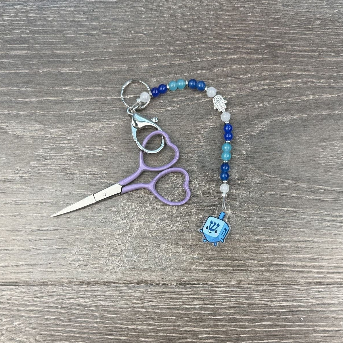 Keychain with scissors and beaded scissor fob attached on a wooden surface