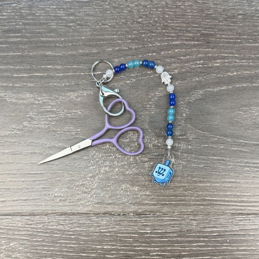 Keychain with scissors and beaded scissor fob attached on a wooden surface