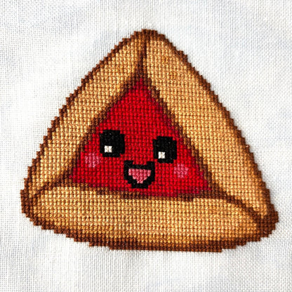 Cross-stitched design of a smiling red hamantaschen on white linen fabric