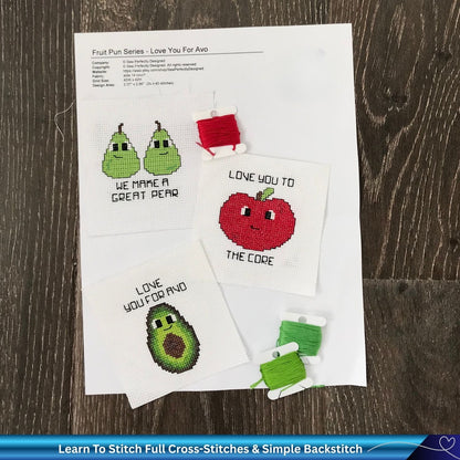 Cross-stitched patterns of fruits and vegetables on paper with a wooden surface background.
