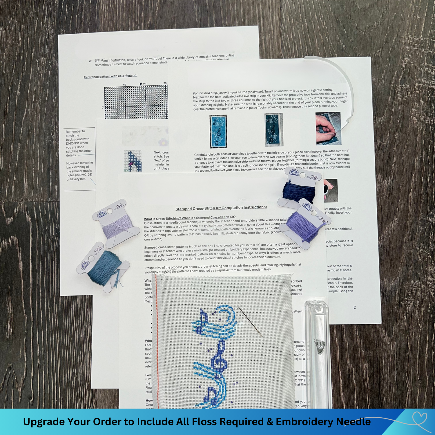 Cross-stitch kit with pattern sheet, floss, and needle on a wooden surface