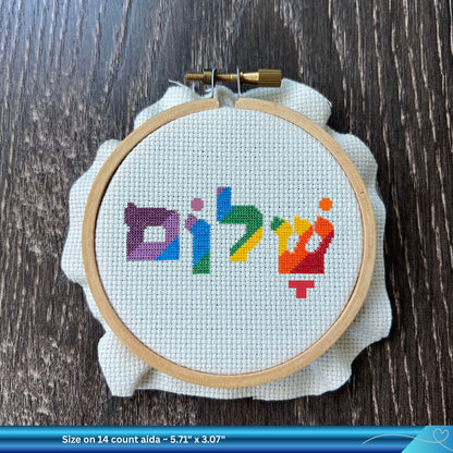 Embroidery hoop with colorful word Shalom cross-stitched design on a white fabric background