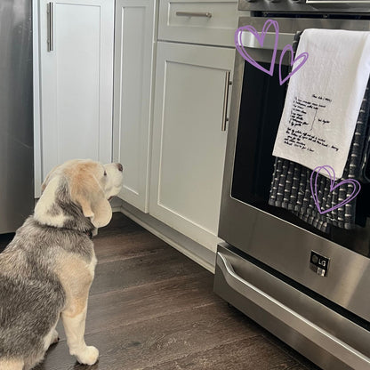 Dog looking at a hand embroidered dish towel with family recipe 