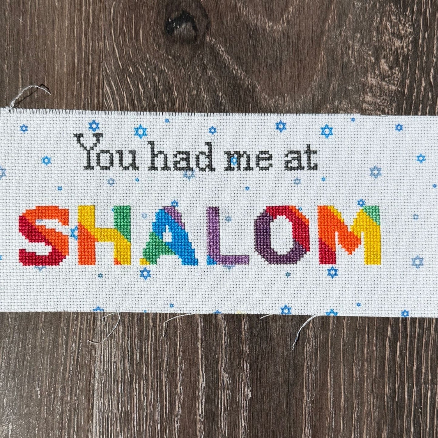 Cross-stitched banner with 'You had me at SHALOM' text on a wooden background