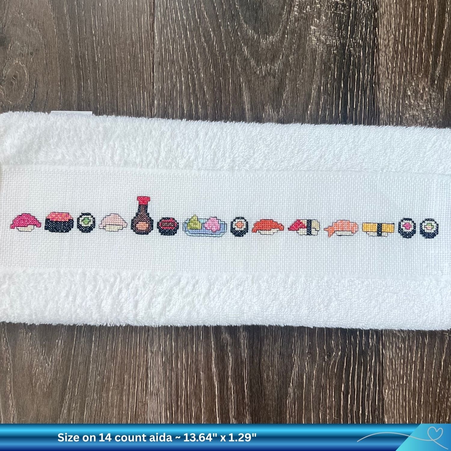Cross-stitched sushi pattern on a white towel with text about size of design on 14 count Aida fabric