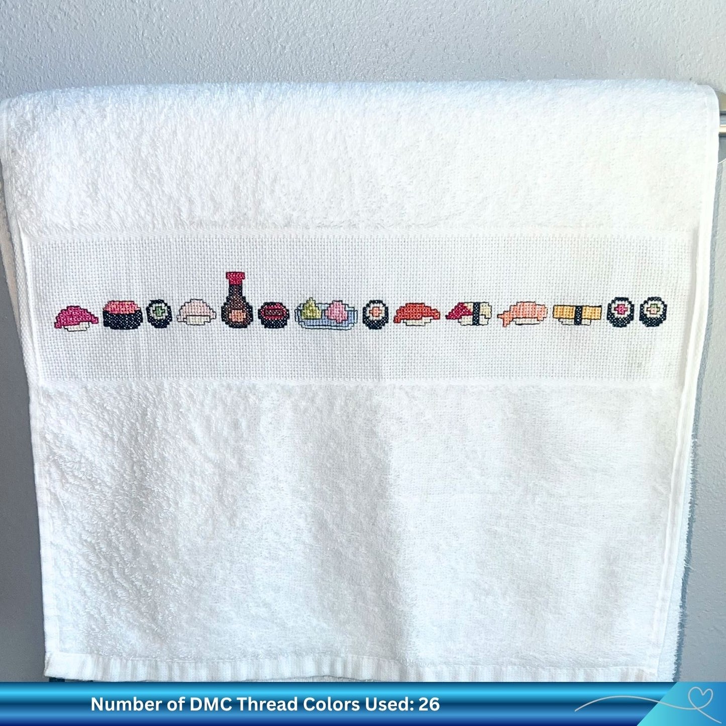 Cross-stitched sushi pattern on a white towel with a gray textured background