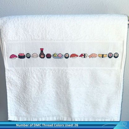 Cross-stitched sushi pattern on a white towel with a gray textured background