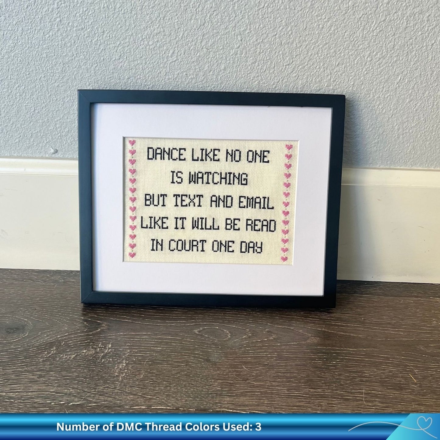 Cross stitch pattern with the phrase "dance like no one is watching but text and email like it will be read in court one day" framed against the wall.