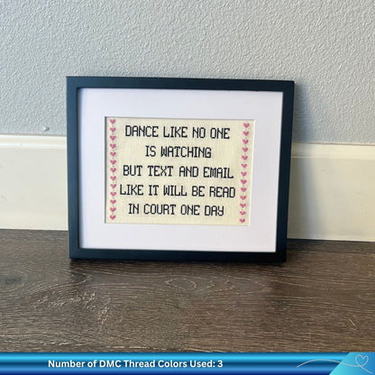 Cross stitch pattern with the phrase "dance like no one is watching but text and email like it will be read in court one day" framed against the wall.