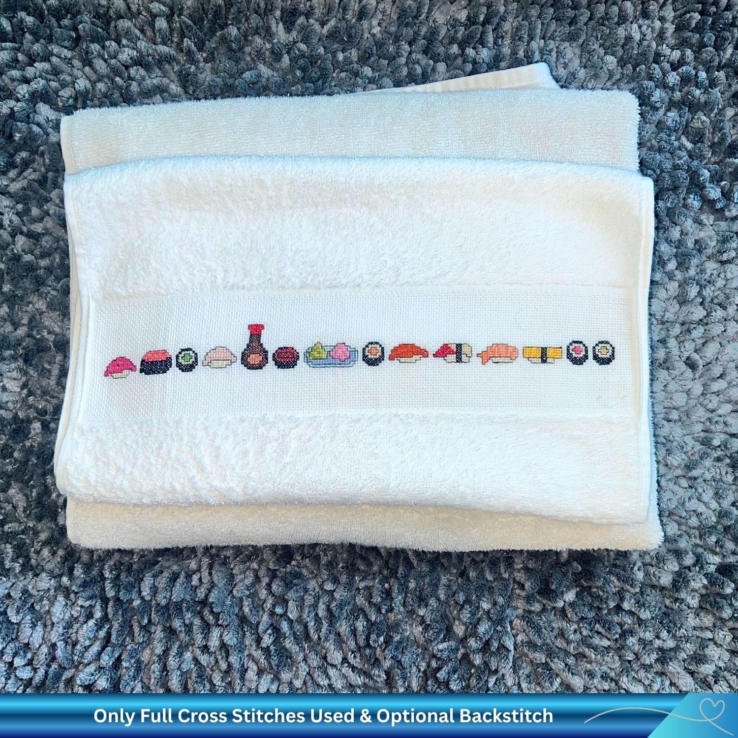 Folded towel with cross-stitched sushi design on a textured surface