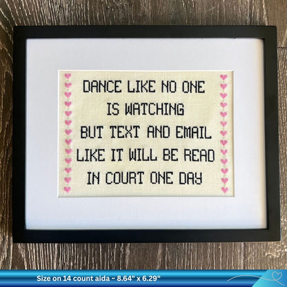 Framed humorous legal cross-stitched text on a wooden surface
