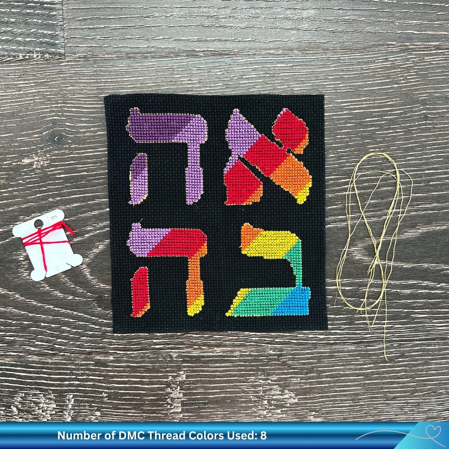 Hand embroidery cross-stitched pattern of the word Love (Ahava) with a golden thread against a wooden background