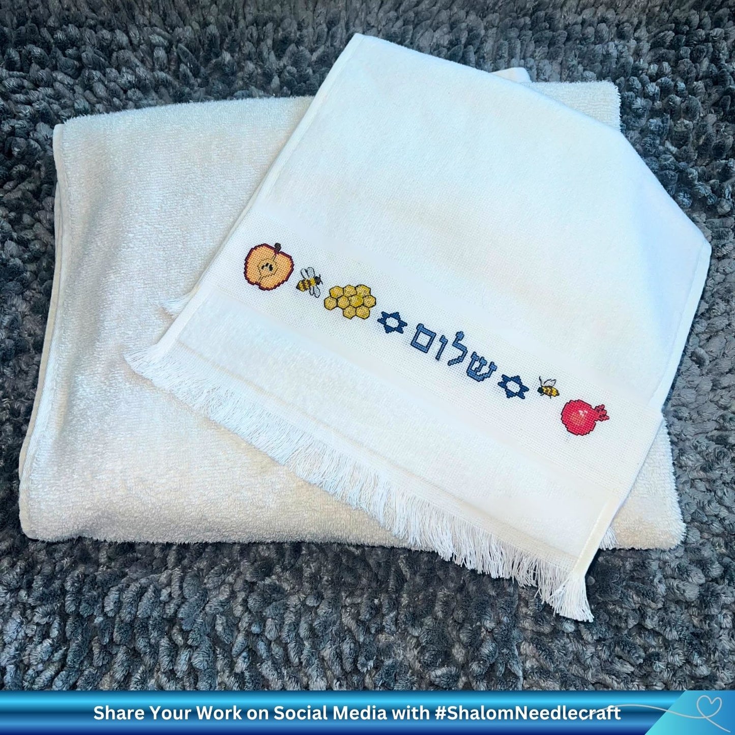 Folded white hand towel with embroidered Jewish Rosh Hashanah cross-stitch designs 