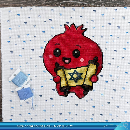 Cross-stitch pattern of a red Pomegranate holding a Torah scroll with blue thread on a white Aida fabric background.