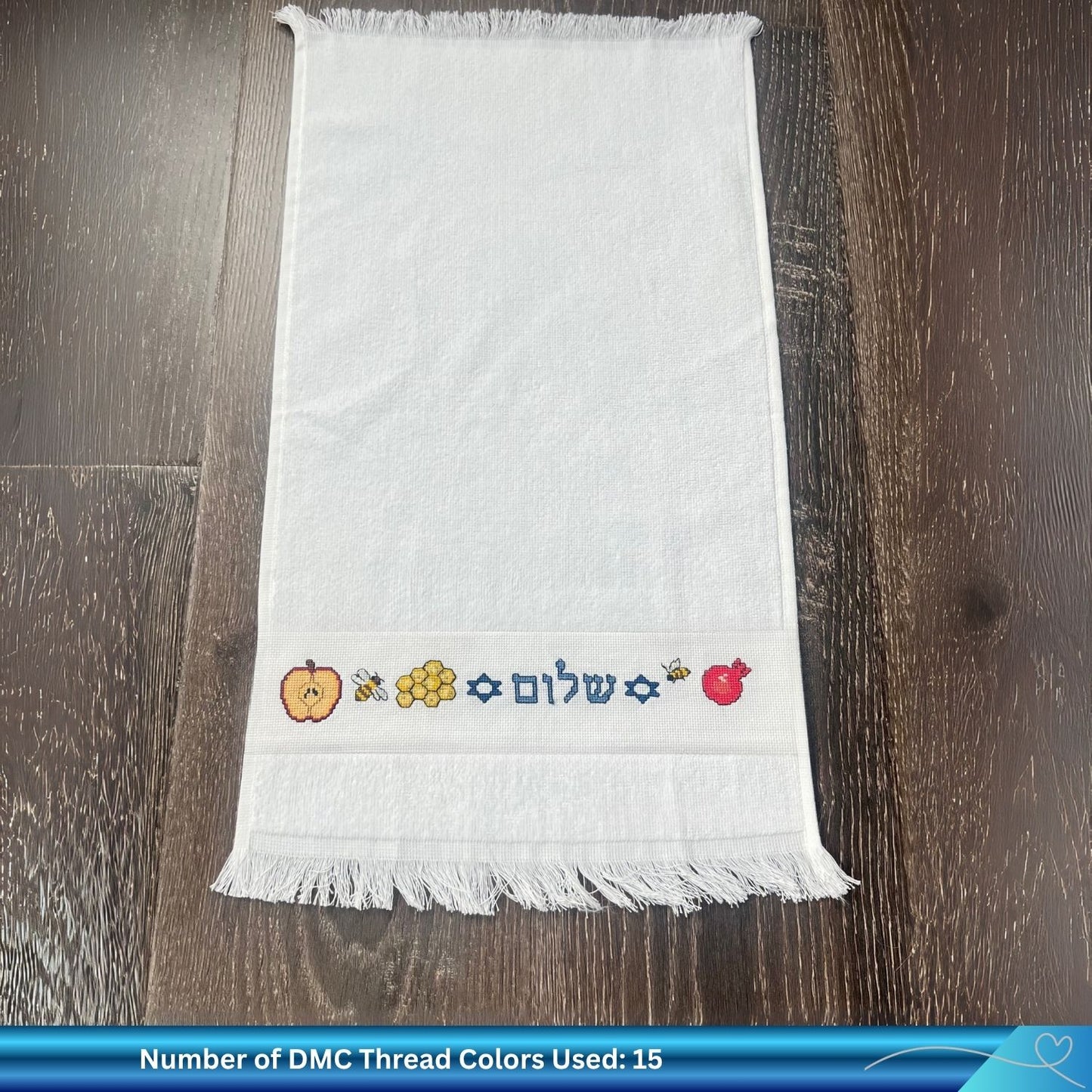 Embroidered towel with colorful Jewish New Year designs on a wooden surface
