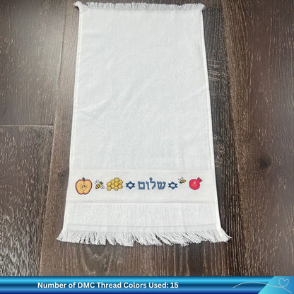 Embroidered towel with colorful Jewish New Year designs on a wooden surface