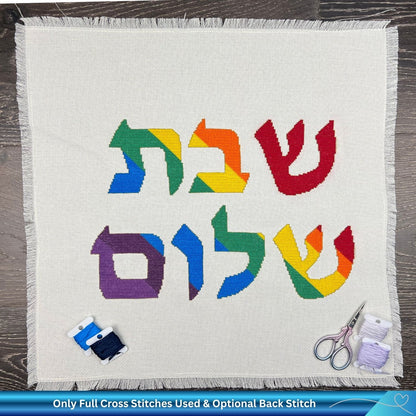 Hand embroidered cotton challah cover with cross-stitched Hebrew design on a wooden surface